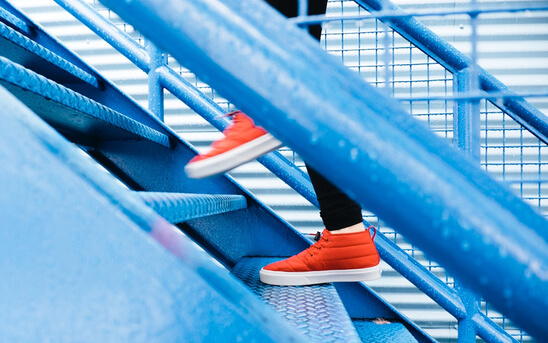 Feet in red sneakers walking up steel stairs